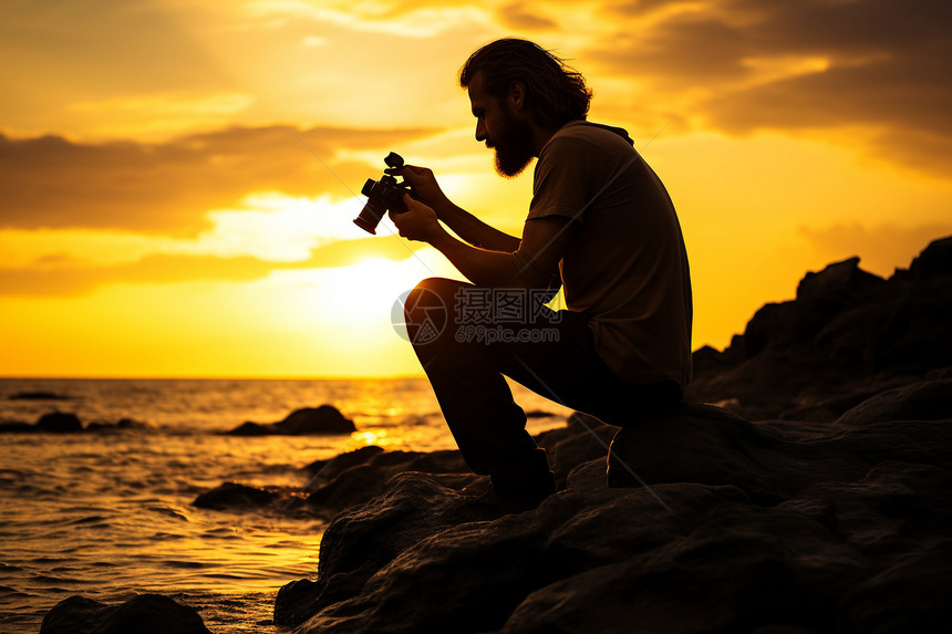 夕阳映照下的摄影师坐在岩石上图片
