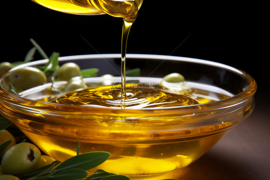 橄榄油洒在带叶的装有橄榄的碗中图片