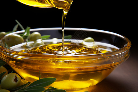 橄榄油洒在带叶的装有橄榄的碗中高清图片