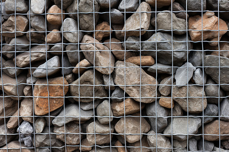 石头堆积在铁网边背景图片