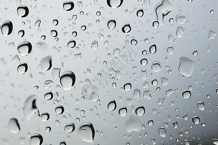 透明玻璃上滴落的雨滴背景图片