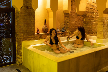 热拉提两名妇女西牙格拉纳达安达卢西亚享受阿拉伯浴埃尔维拉浴冷水池两个女人格拉纳达享受阿拉伯浴背景