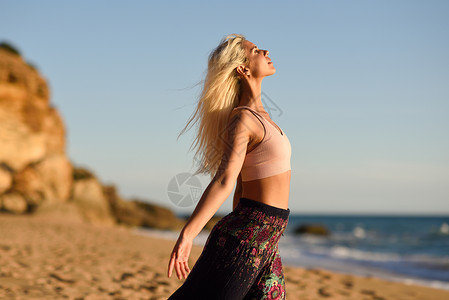 美丽的女人在海边享受日落和海风图片