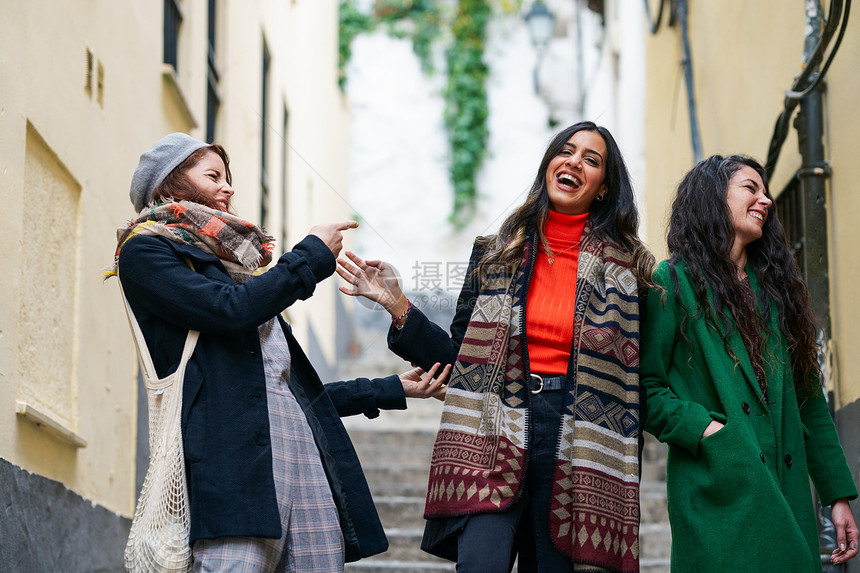 三个快乐女性城市背景下行走的多民族群体三个快乐的女人户外散步的多民族群体图片