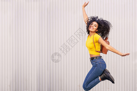 快乐的阿拉伯女人城市背景下跳跃阿夫罗发女快乐的阿拉伯女人跳跃城市背景图片