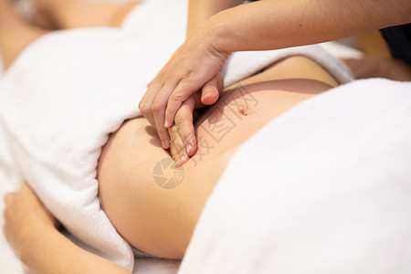 水疗沙龙接受腹部按摩的女人女性患者正接受专业骨病治疗师的治疗女性水疗沙龙接受腹部按摩背景