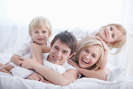 卧室里白色床上的幸福家庭图片
