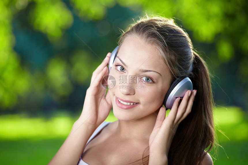 个年轻女孩用耳机听音乐的肖像图片