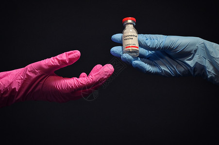 女人用手套给另只手注射冠状病疫苗高清图片