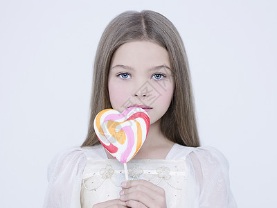 小漂亮的女孩带着大糖果工作室阿什翁摄影的孩子穿着白色连衣裙吃甜棒棒糖的美女模特图片