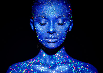蓝色闪耀光辉时尚模特女人穿着蓝色明亮的火花霓虹灯工作室摆姿势美丽性感女人的肖像艺术彩色闪光发光化妆背景