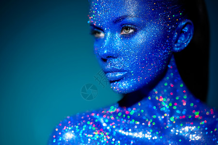 蓝色闪耀光辉时尚模特女人穿着蓝色明亮的火花霓虹灯工作室摆姿势美丽性感女人的肖像艺术彩色闪光发光化妆背景