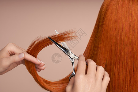 发型红色理发师用剪刀剪红色的长发发廊,发型师护理美容美发产品染了头发背景
