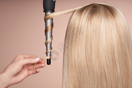 理发师用卷发熨斗卷发长着直发的漂亮女人光滑的发型背景图片