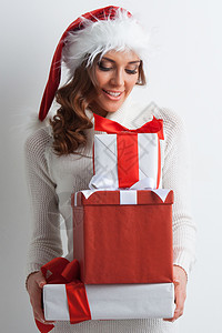 微笑可爱的女孩戴着圣诞帽,带着红色的圣诞礼盒带圣诞礼盒的女孩图片