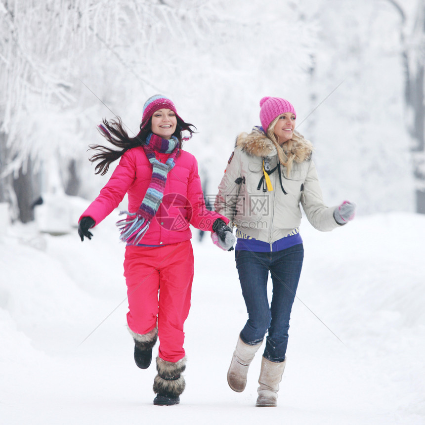 两个年轻的快乐微笑的女人冬天的公园里跑步两个女人冬季公园跑步图片