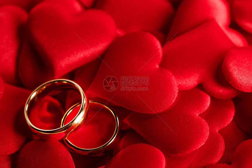 红色缎心背景上的两个金色结婚戒指红色的金色结婚戒指图片