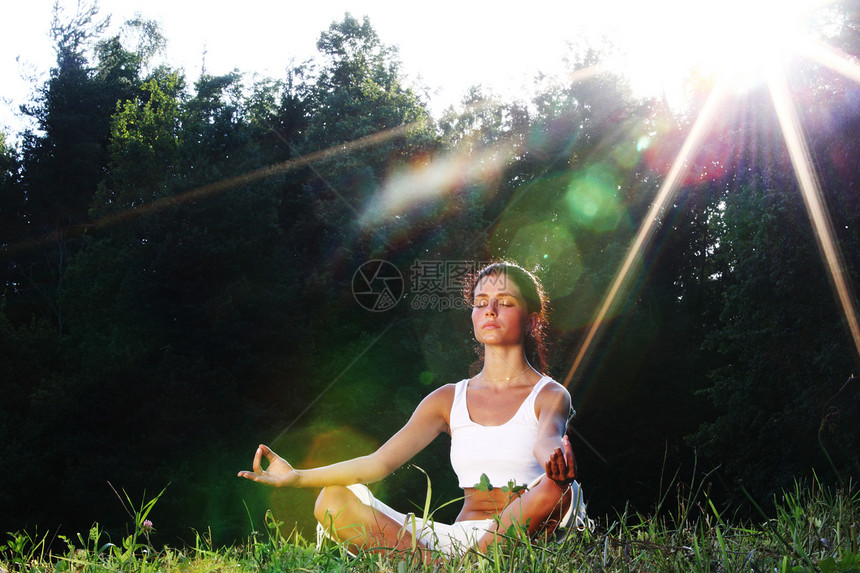 年轻的瑜伽女子绿草莲花姿态日出的光线公园里做瑜伽的女人图片