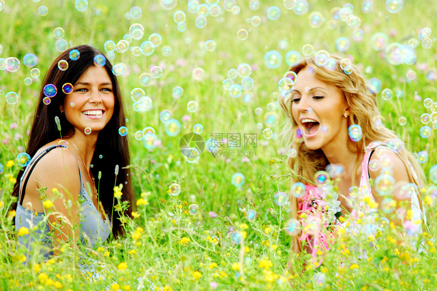 肥皂泡的绿草地上快乐地拍打女朋友夏天草地上的女朋友图片