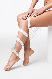 特写完美的女性腿与白色丝带白色背景女人的腿上有白色的丝带图片