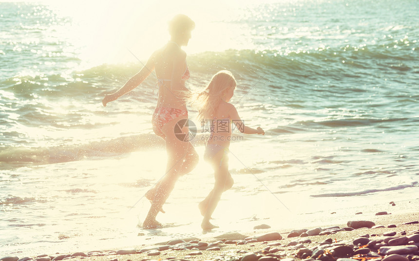 日落时海滩上的家人母女俩起跑步图片