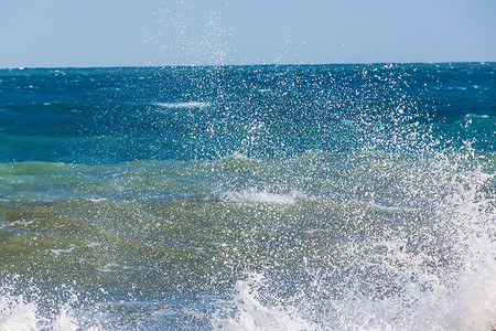 海滩上的蓝色波浪模糊背景阳光斑点戏剧的自然背景图片