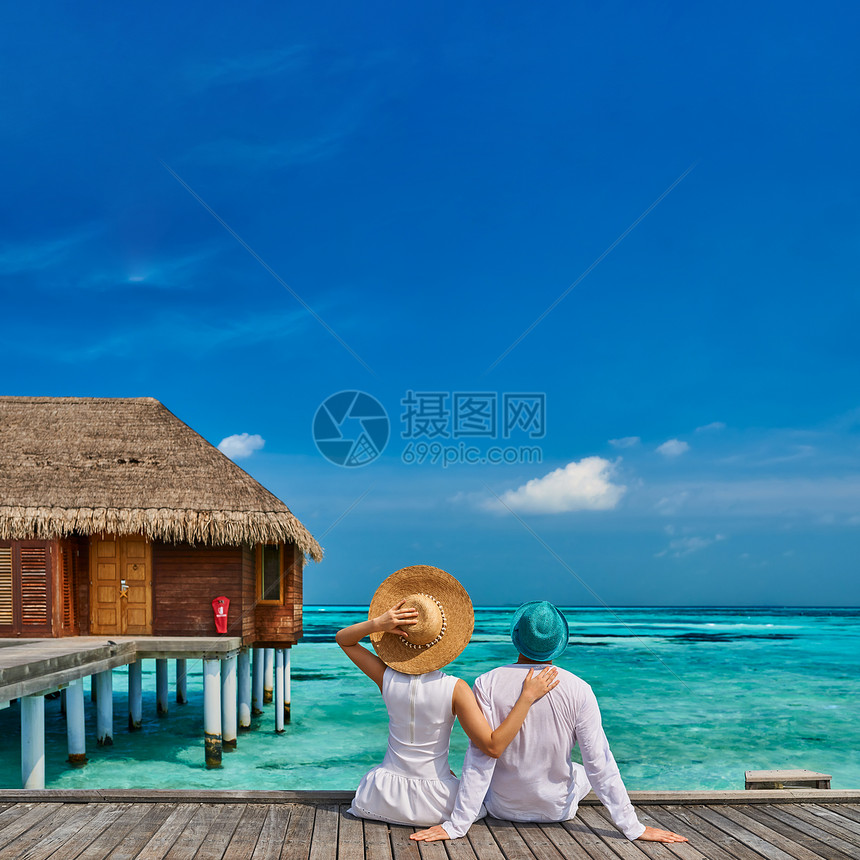 穿着白色衣服的夫妇马尔代夫水上别墅附近的热带海滩码头上图片