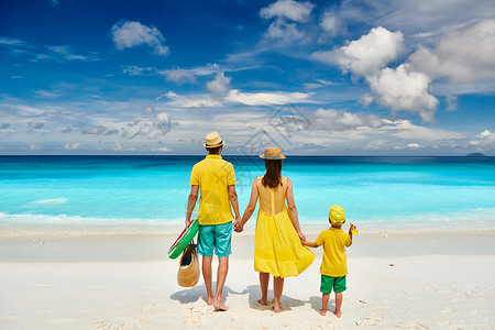 家庭美丽的娇小的Anse海滩,穿着黄色衣服的年轻夫妇三岁的蹒跚学步的男孩马赛尔的暑假背景图片