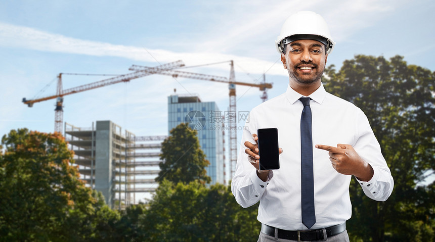 建筑,建筑业务人的微笑的印度男建筑师头盔智能手机建筑现场背景建筑师建筑工地展示智能手机图片