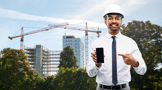 通信工人建筑,建筑业务人的微笑的印度男建筑师头盔智能手机建筑现场背景建筑师建筑工地展示智能手机设计图片