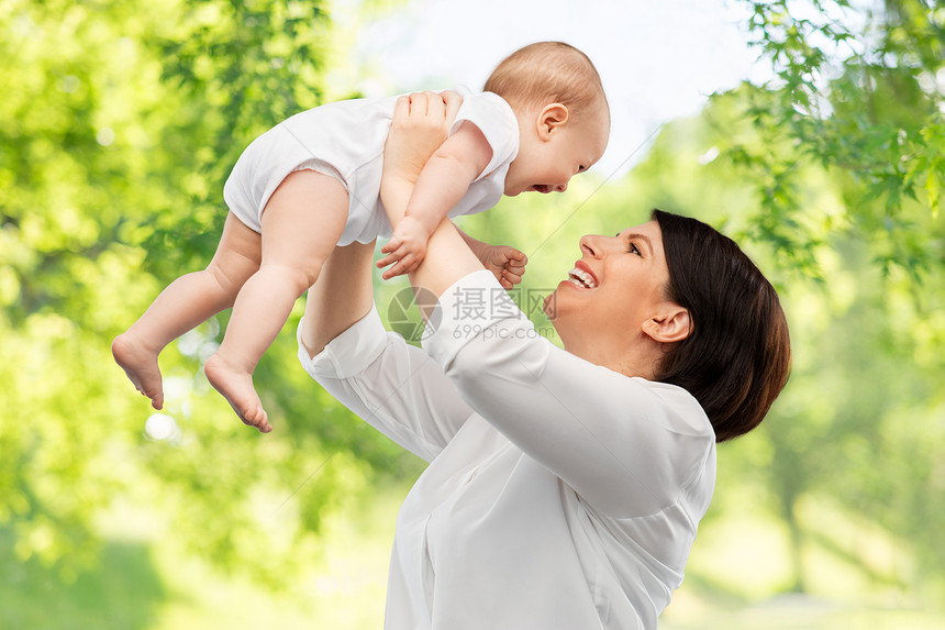 家庭,孩子父母的快乐的微笑中年母亲抱着小宝贝女儿绿色的自然背景快乐的中年母亲小女儿图片