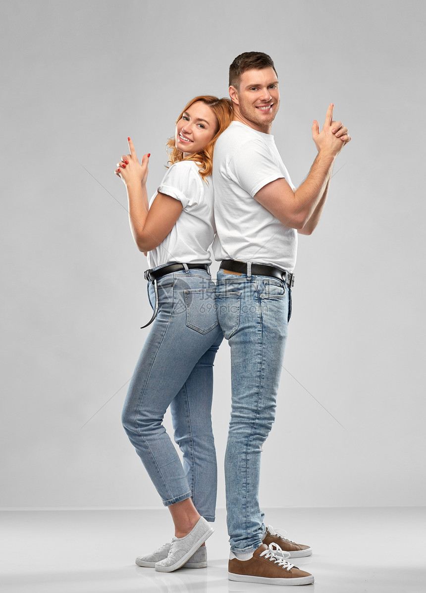 关系人的幸福的夫妇白色T恤上做手势灰色背景上的肖像穿着白色T恤衬衫的夫妇做着的手势图片