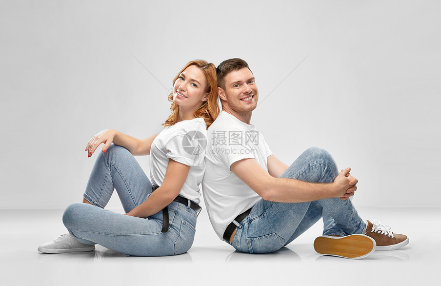 关系,风格人的幸福的夫妇穿着白色T恤坐地板上的灰色背景穿着白色T恤的幸福夫妇坐地板上图片