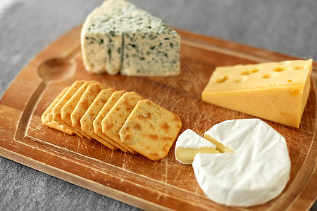 食物饮食同种类的奶酪咸饼干木制切割板上木板上有同的奶酪饼干图片