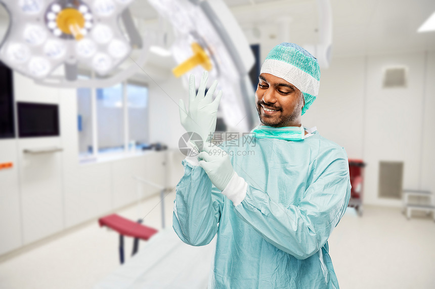 医学,外科人的微笑的印度男医生或外科医生穿着防护服,医院背景下手术室戴上手套印度男医生或外科医生医院图片
