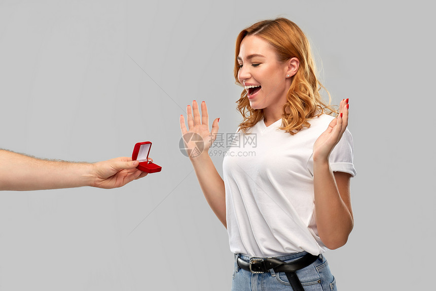 爱情,夫妻,求婚人的男人小红盒子里给灰色背景下快乐的女人钻石订婚戒指男人情人节给女人订婚戒指图片