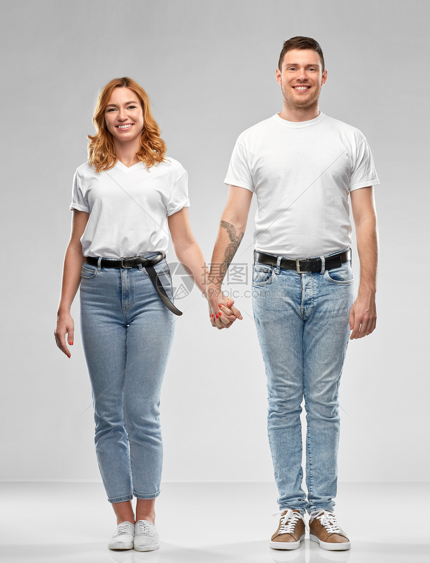 关系人的幸福的夫妇穿着白色T恤,手牵着手灰色背景上穿着白色T恤的幸福夫妇牵手图片