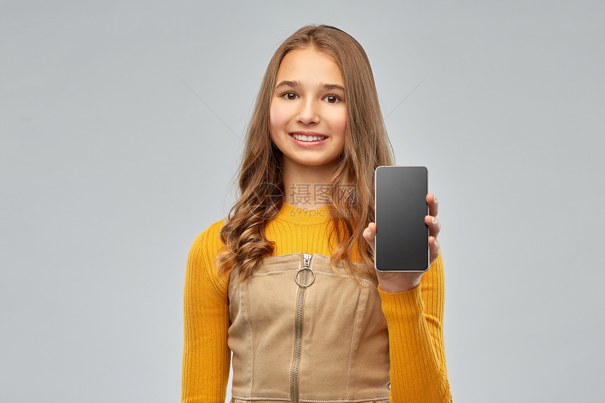 技术,沟通人的微笑的十几岁女孩空白屏幕的智能手机灰色背景微笑的少女展示智能手机图片