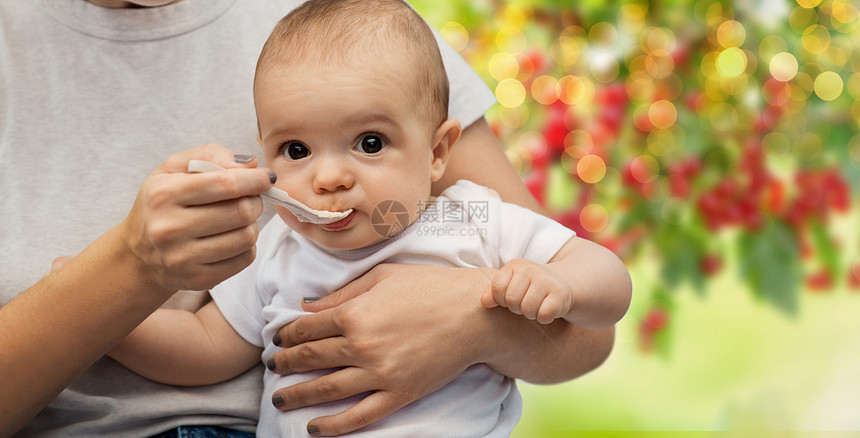 孩子,饮食食物的母亲用勺子喂养小婴儿绿色的自然背景用勺子喂小宝宝来亲近妈妈图片