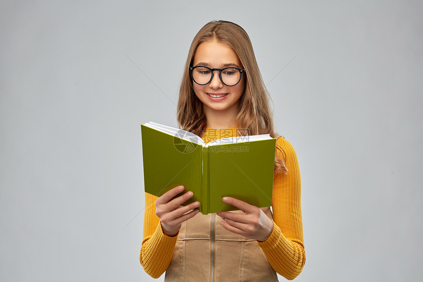 高中,教育视觉微笑的十几岁的学生女孩眼镜阅读书的灰色背景十几岁的学生女孩戴着眼镜看书图片