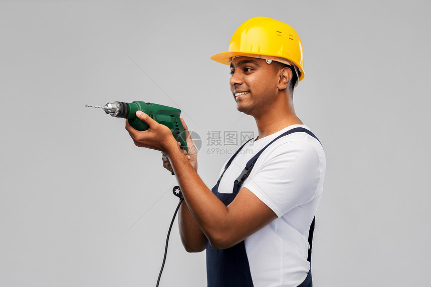 专业,建筑建筑快乐的微笑印度工人或建筑工人头盔与电钻或穿孔灰色背景快乐的印度建筑工人戴着电钻的头盔图片
