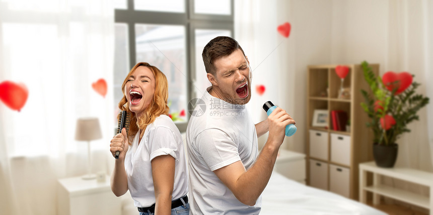 情人节,乐趣人的幸福夫妇白色T恤夫妇唱歌的梳子洗剂瓶家庭卧室装饰心形气球背景夫妇家里唱歌给梳子乳液图片