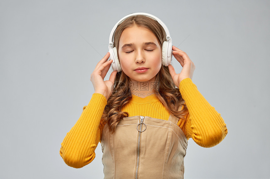 音频设备技术人员的微笑的十几岁女孩耳机听轻松的音乐灰色背景戴耳机听放松音乐的十几岁女孩图片
