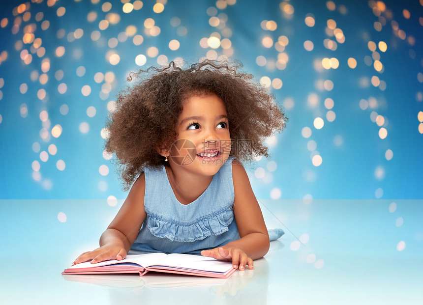 童年,学校教育快乐微笑的非裔美国女孩阅读书节日灯蓝色背景微笑的非裔美国女孩看书图片