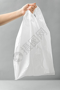 消费主义生态友好的妇女持有白色次塑料袋灰色背景女人着白色次塑料袋图片