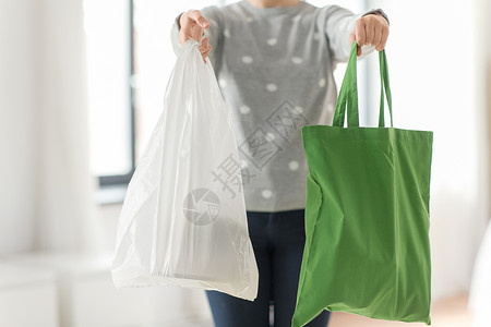 写实带扎绳塑料袋消费主义生态友好的妇女持有可重复用的帆布手提包,用于食品购物塑料袋的灰色背景带手提包购物塑料袋的女人背景