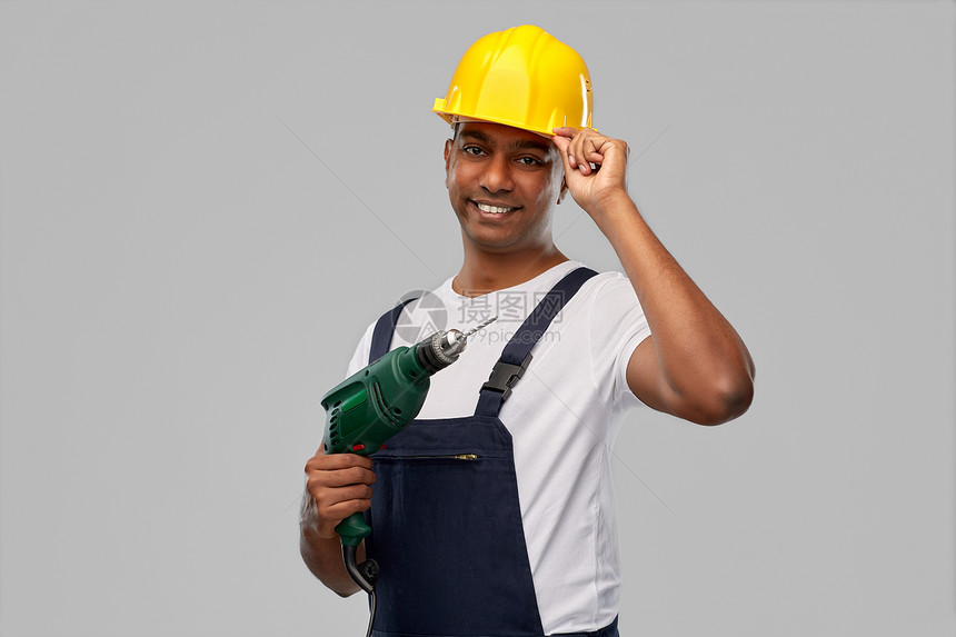 专业,建筑建筑快乐的微笑印度工人或建筑工人头盔与电钻或穿孔灰色背景快乐的印度建筑工人戴着电钻的头盔图片