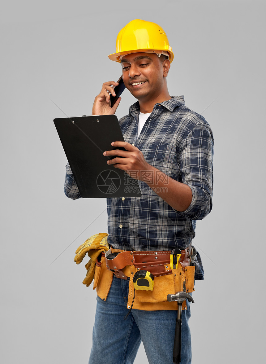 专业,建筑建筑快乐的微笑印度工人或建筑工人头盔与剪贴板呼叫智能手机灰色背景印度建筑工人头盔调用智能手机图片