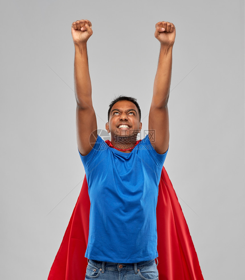 超级力量人的印度男人穿着红色超级英雄斗篷,灰色背景上做获胜的手势穿着超级英雄斗篷的印度男人做了获胜的手势图片