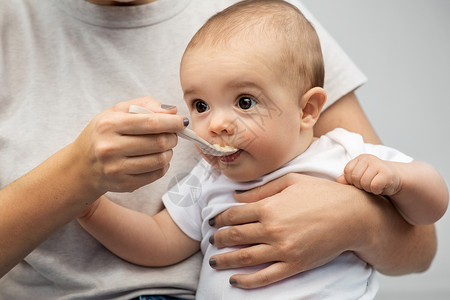孩子,吃食物的密切母亲用勺子喂养小婴儿用勺子喂小宝宝来亲近妈妈背景图片